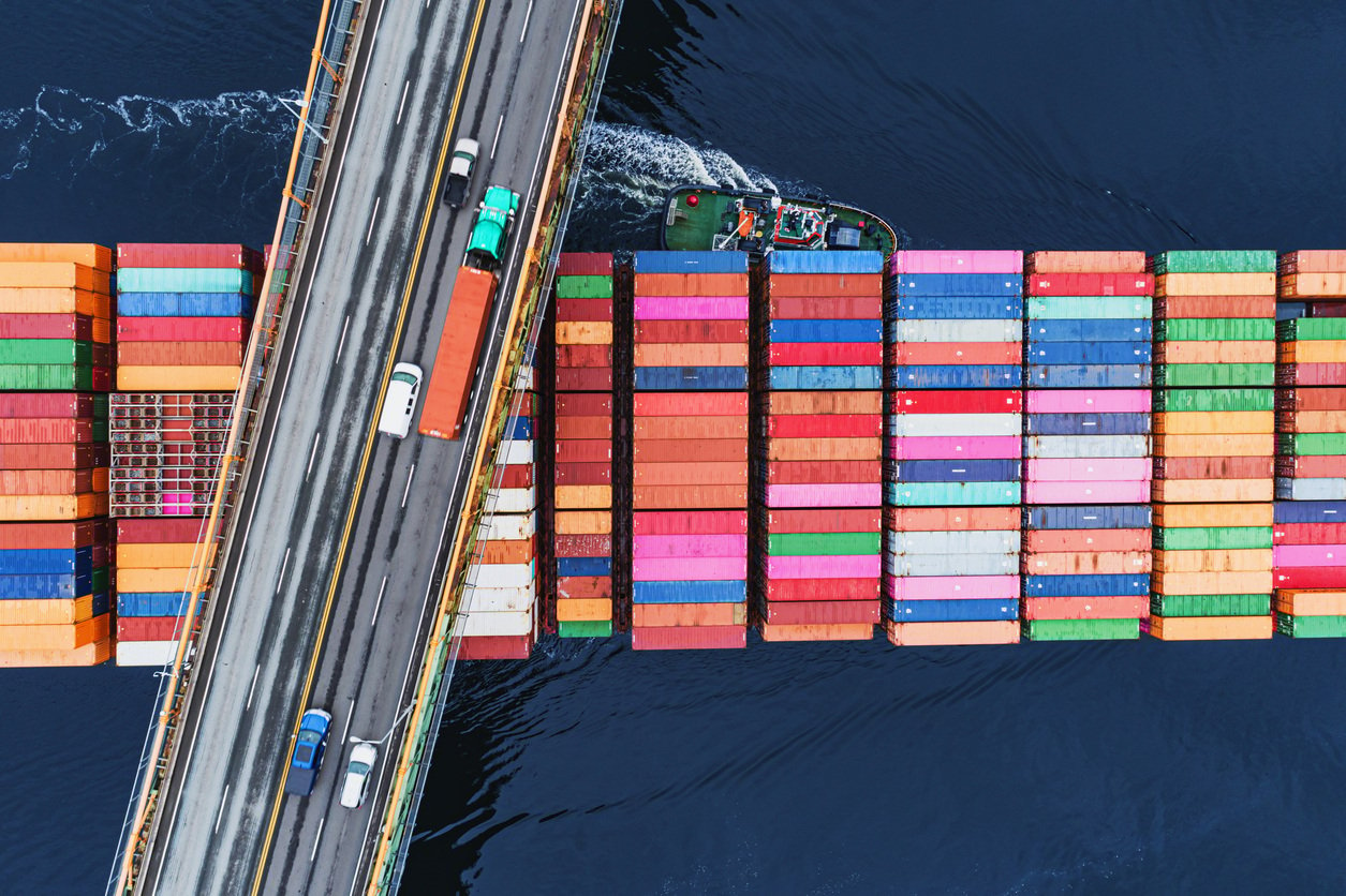 cargo ship passing under traffic bridge